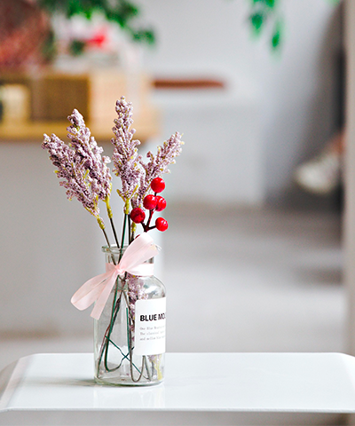 Pequeño arreglo floral en frasco de vidrio con lazo rosado