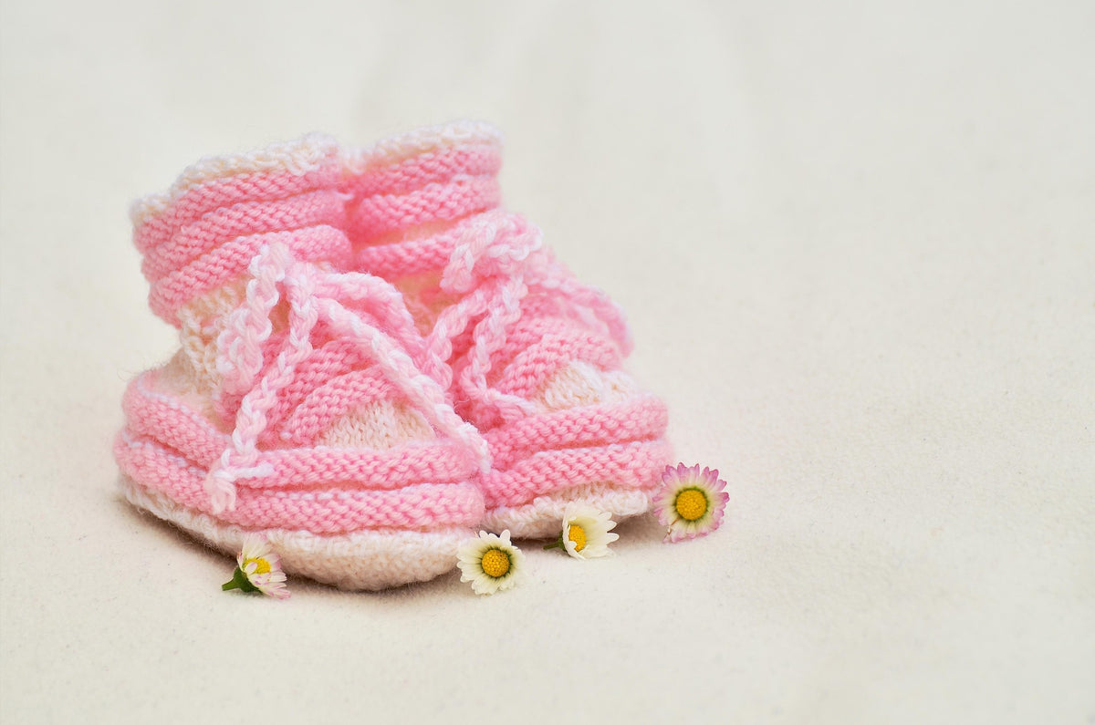 Zapatitos de bebé tejidos rosados con margaritas, flores para nacimientos